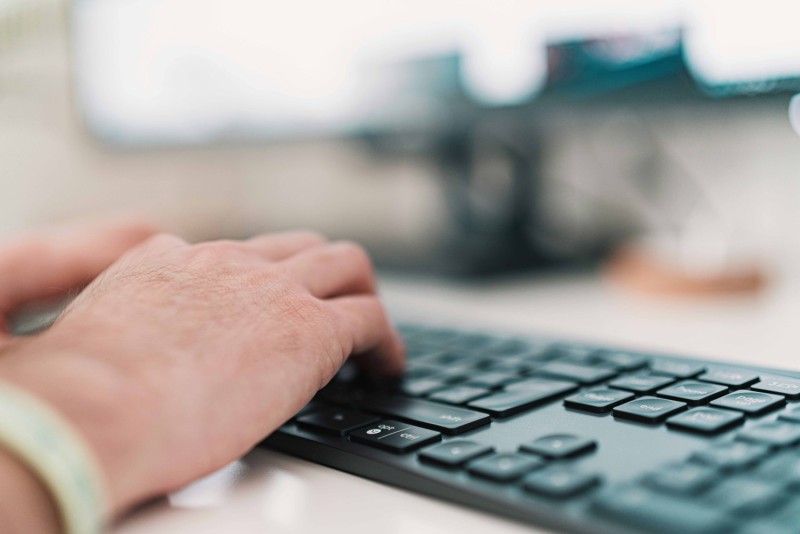 Main qui tape sur le clavier d'un ordinateur pour illustrer la rédaction SEO