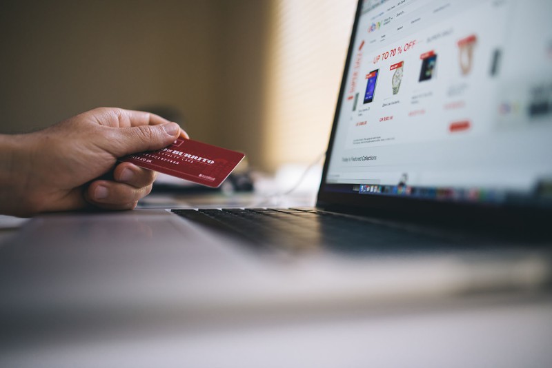 Ordinateur montrant une boutique en ligne et la main d'une personne avec une carte bleue